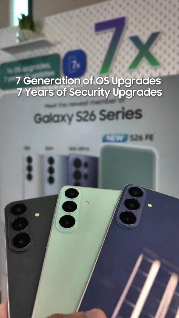 Tiga unit Galaxy S26 FE warna Graphite, Pistachio dan Blueberry dipegang depan papan info siri S26