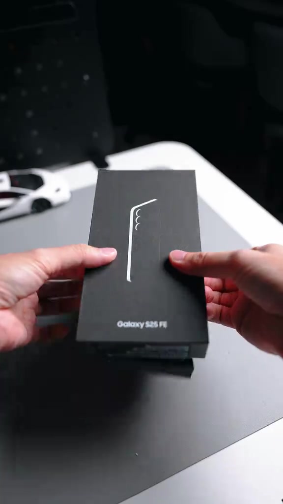 Kotak hitam Galaxy S25 FE dipegang dua tangan semasa unboxing