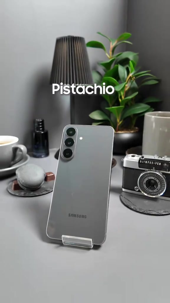 Galaxy S26 FE warna Pistachio berdiri atas stand di atas meja