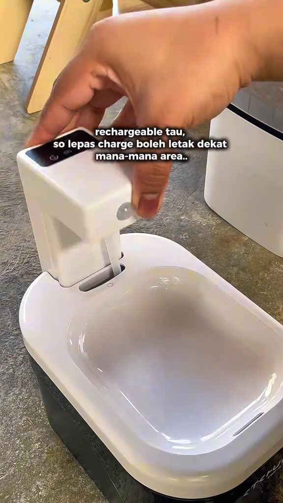 Tangan mengangkat unit pam kecil water fountain yang boleh dicas keluar dari tangkinya