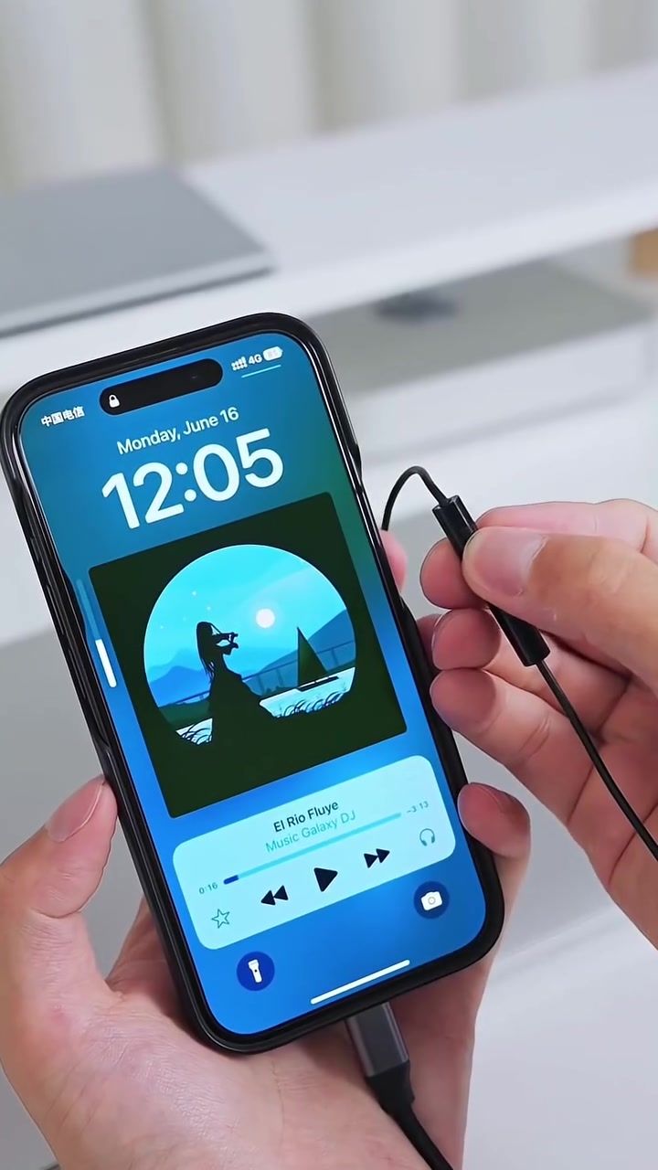 Tangan memegang telefon dengan muzik sedang dimainkan dan earphone berwayar dicucuk pada port bawah