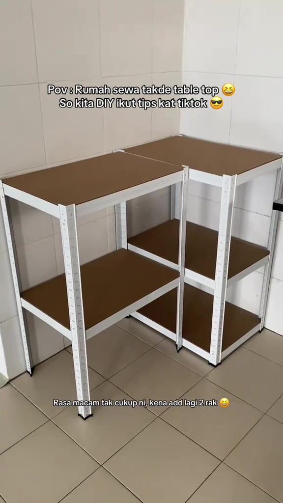 Dua rak besi putih berpapan coklat disusun bentuk L menjadi table top dapur rumah sewa