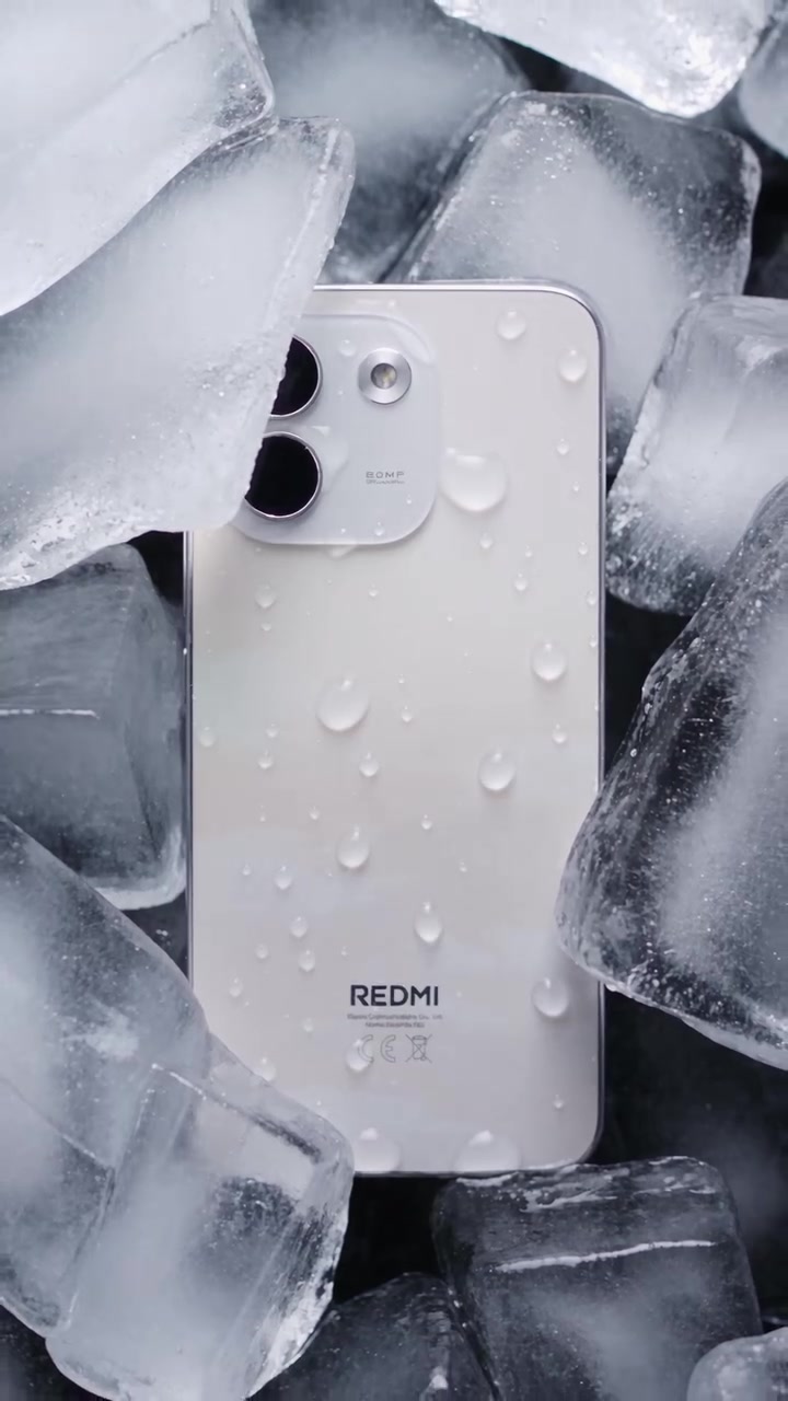 Bahagian belakang REDMI Note 17 warna putih dengan titisan air, diletak di celah ketulan ais
