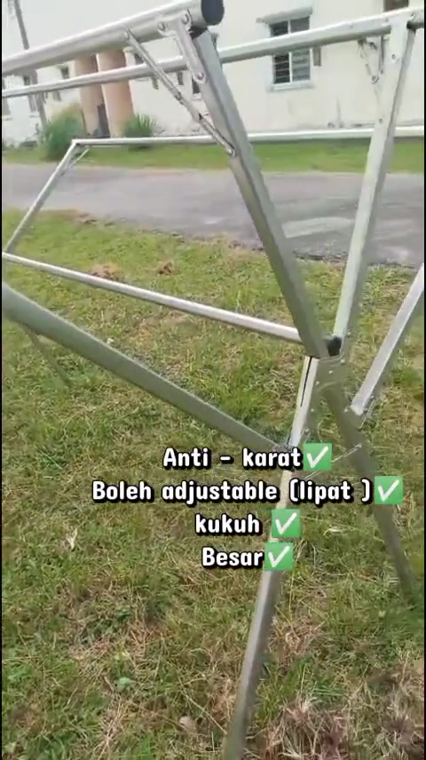 Rangka ampaian wing stainless steel berdiri atas rumput, nampak jelas sambungan silang bahagian tengah