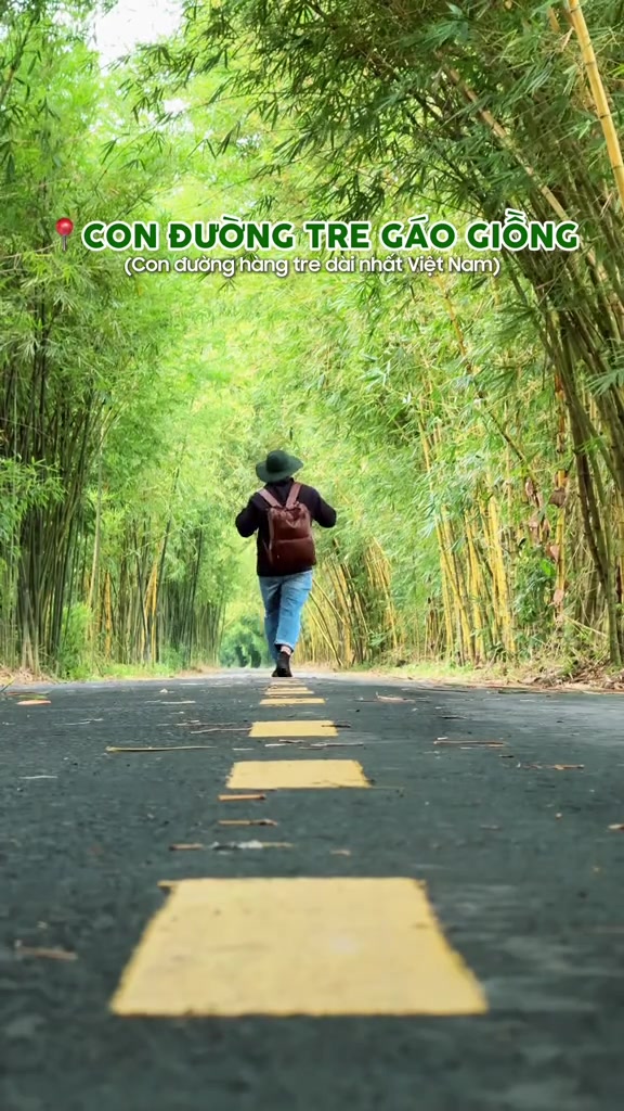 Một người đội mũ và đeo ba lô đi bộ dưới vòm tre trên con đường Gáo Giồng, nhìn từ phía sau
