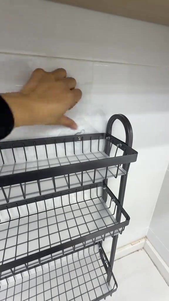 Tangan menekan pad pelekat rak dinding pada jubin putih dapur