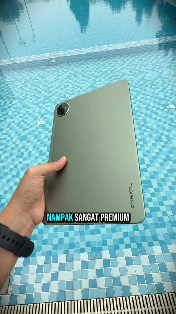 Bahagian belakang NEXAL Pad warna hijau dipegang dengan satu tangan berlatar kolam renang