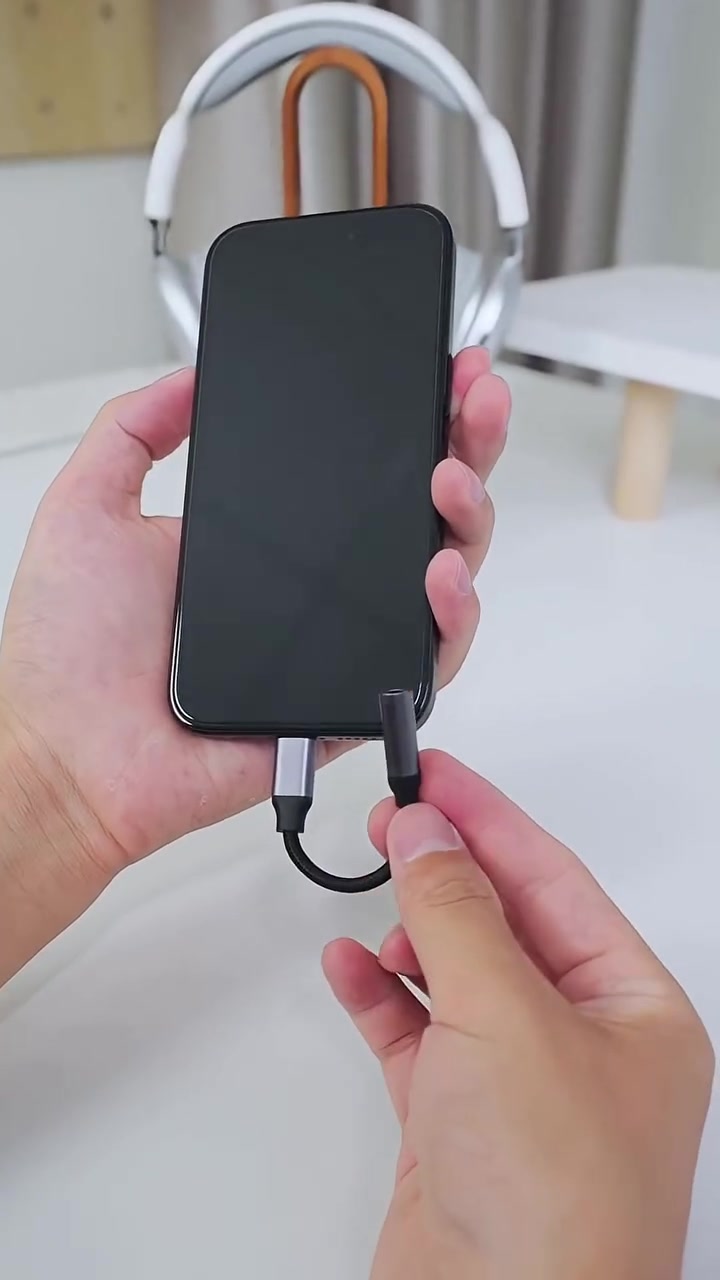 Adapter USB-C ke jack 3.5mm disambung pada bahagian bawah telefon yang dipegang tangan