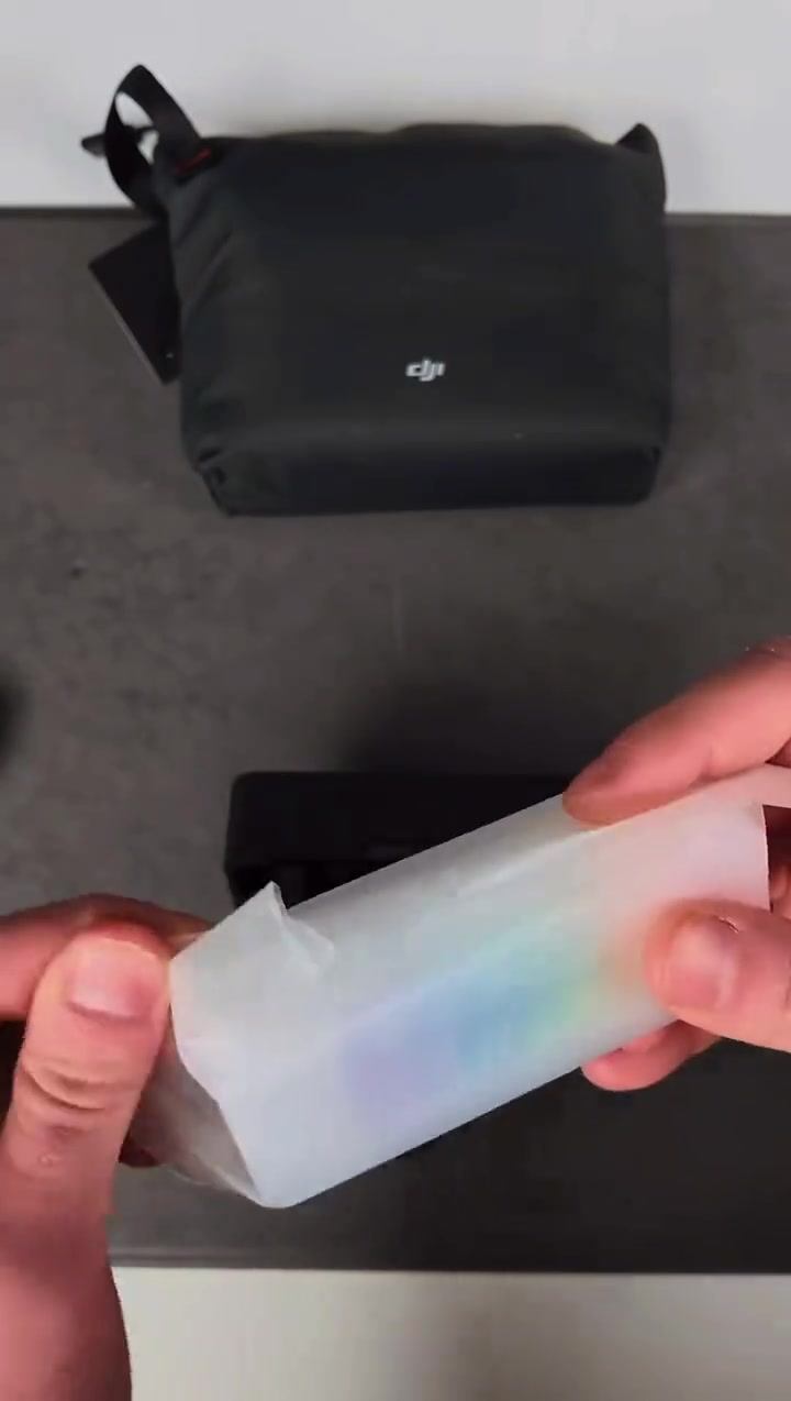 Bekas translucent berisi cover magnetik berwarna-warni untuk transmitter DJI Mic Mini 2S dipegang di tangan