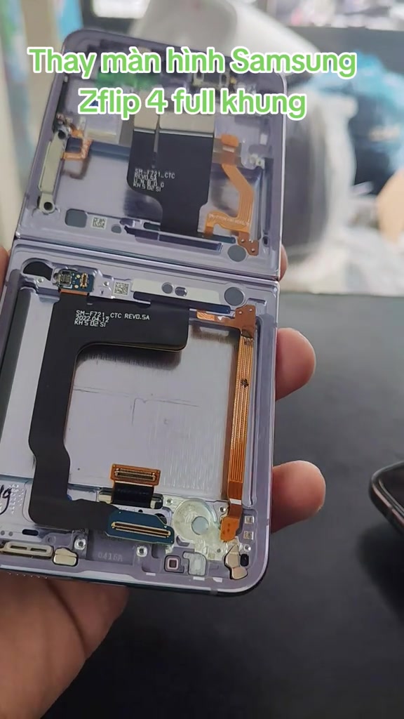 Chiếc Samsung Z Flip4 đã tháo rời thành hai nửa, lộ cáp gập và khung kim loại bên trong, cầm trên tay