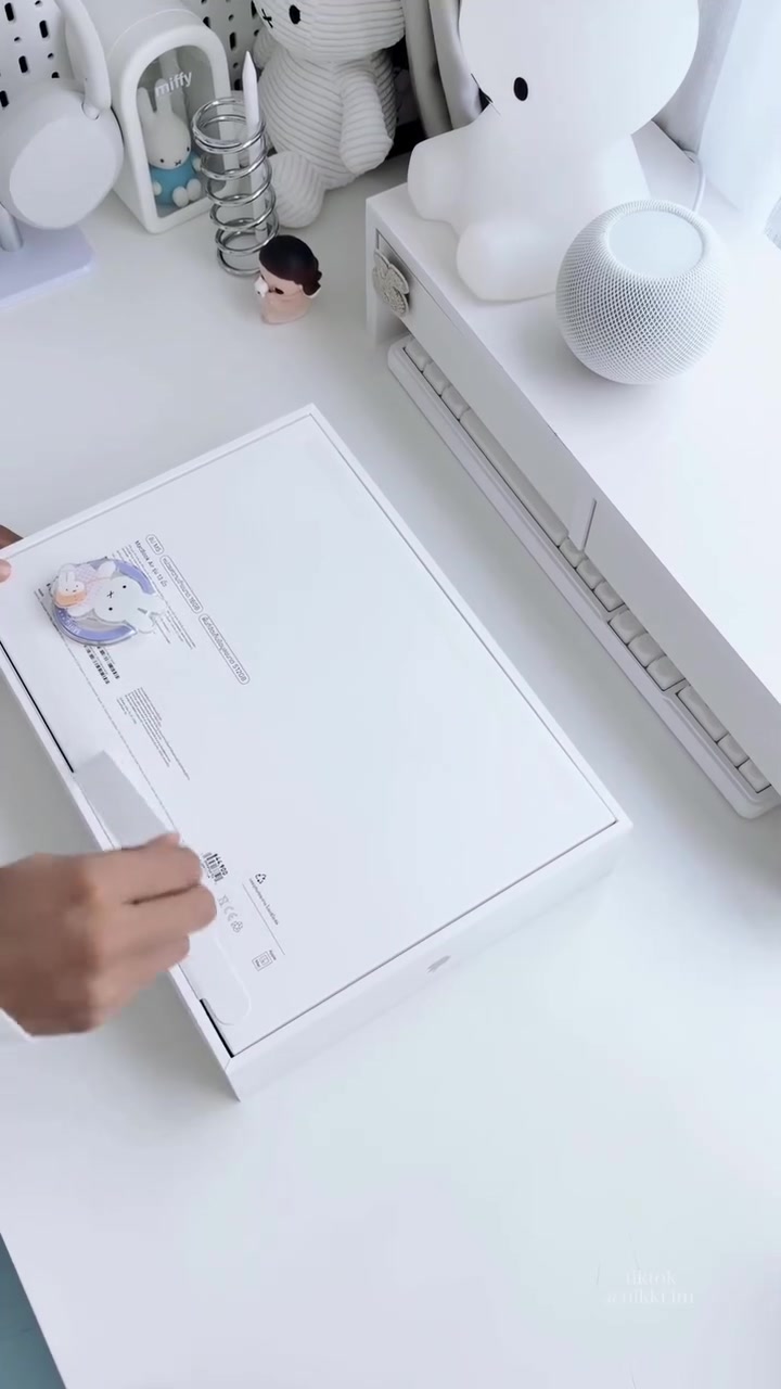Hộp MacBook Air M5 đặt trên bàn trắng cạnh gấu bông và loa HomePod