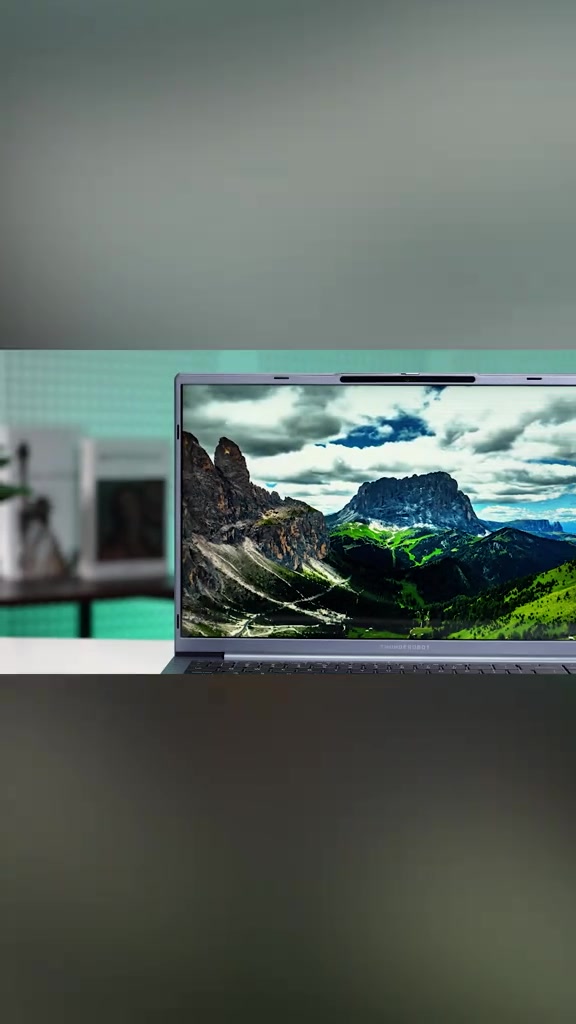 Thân máy màu xám bạc và màn hình hiển thị hình nền núi của laptop Thunderobot T-Book 15A