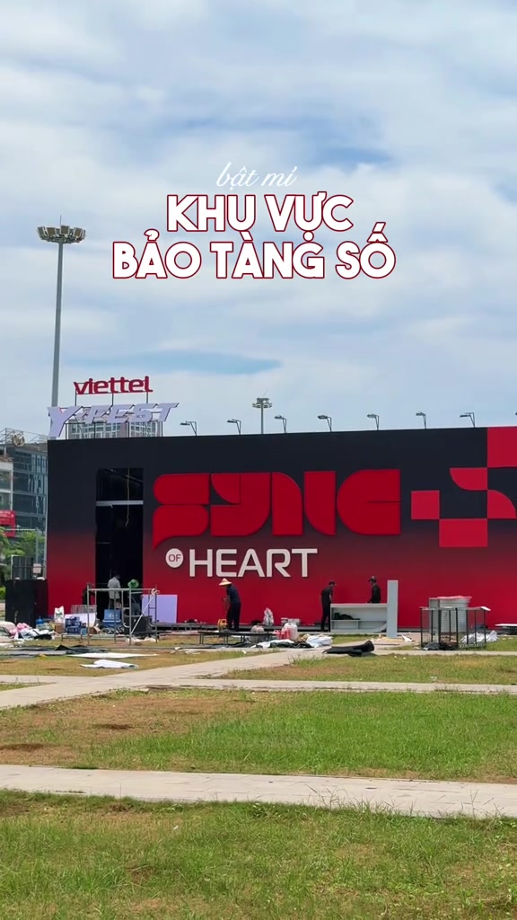 Khu vực trải nghiệm Bảo Tàng Số với tường đỏ đen cỡ lớn tại chặng Y-FEST Quảng Ninh, vài nhân viên kỹ thuật đang setup ở khoảng cách xa