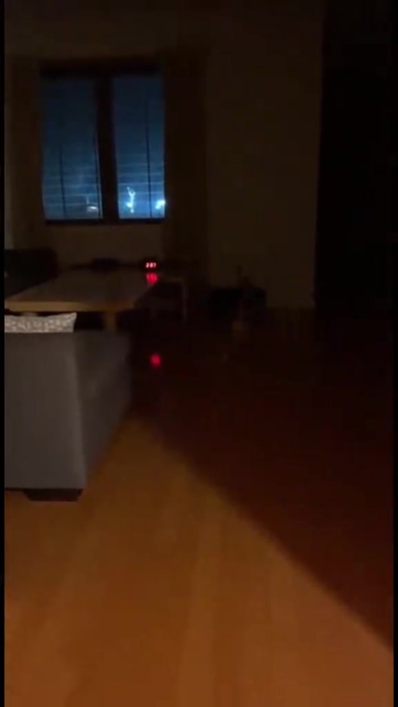 Ruang tamu apartment yang gelap pada waktu malam dengan cahaya samar dari tingkap