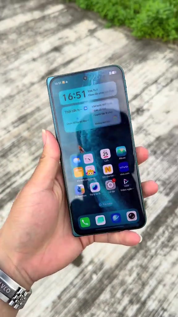 Mặt trước vivo X Fold6 đang hiển thị màn hình chính OriginOS trên màn hình ngoài, cầm trên tay ngoài trời