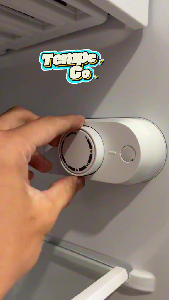 Tangan memusing tombol kawalan suhu bernombor 1 hingga 7 di dalam peti sejuk mini