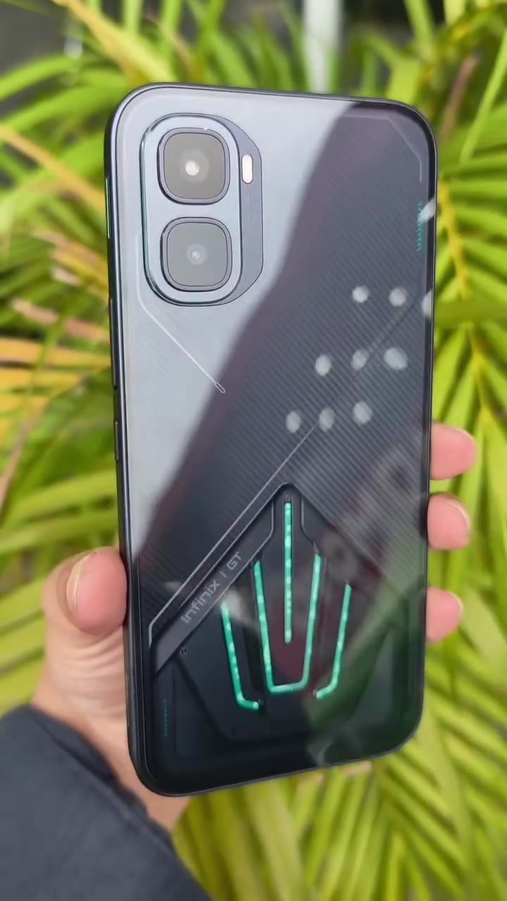 Bahagian belakang Infinix GT 50 Pro warna hitam dengan jalur lampu hijau pada modul penyejukan, dipegang sebelah tangan