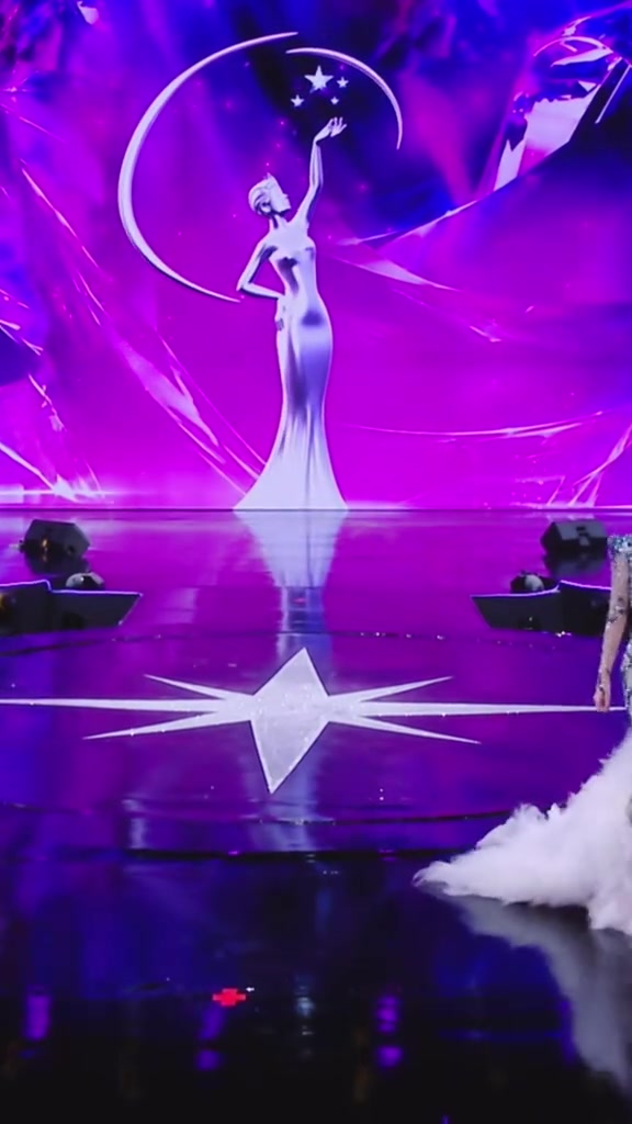 Sân khấu đêm chung kết Miss Universe Vietnam 2026 với màn hình LED hình tượng nữ thần, ngôi sao tám cánh trên sàn và vạt váy lông trắng ở mép phải