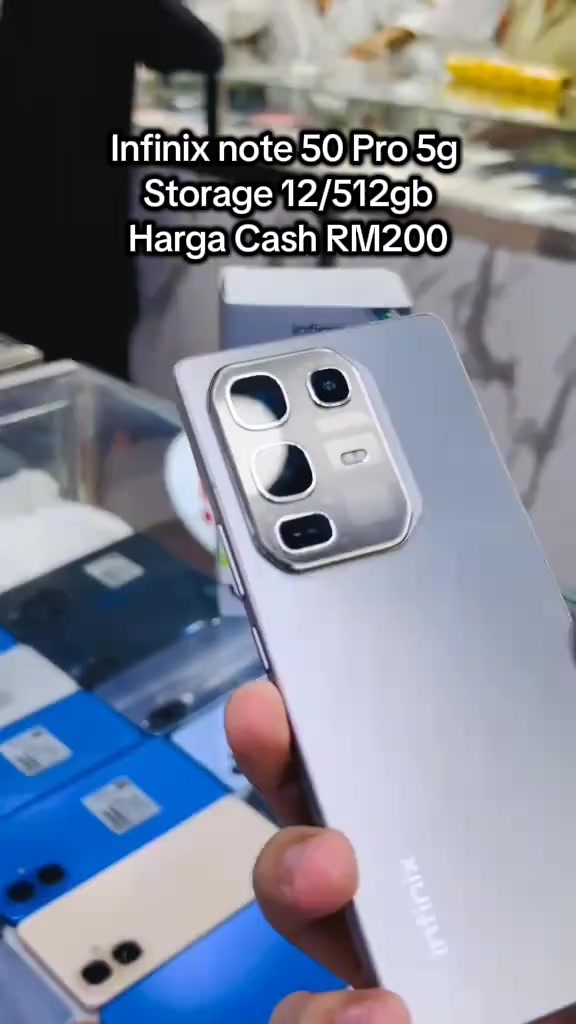 Tangan memegang telefon Infinix NOTE 50 Pro berwarna perak di hadapan kaunter kedai telefon, dengan kapsyen video menyebut storan 12/512GB dan Harga Cash RM200