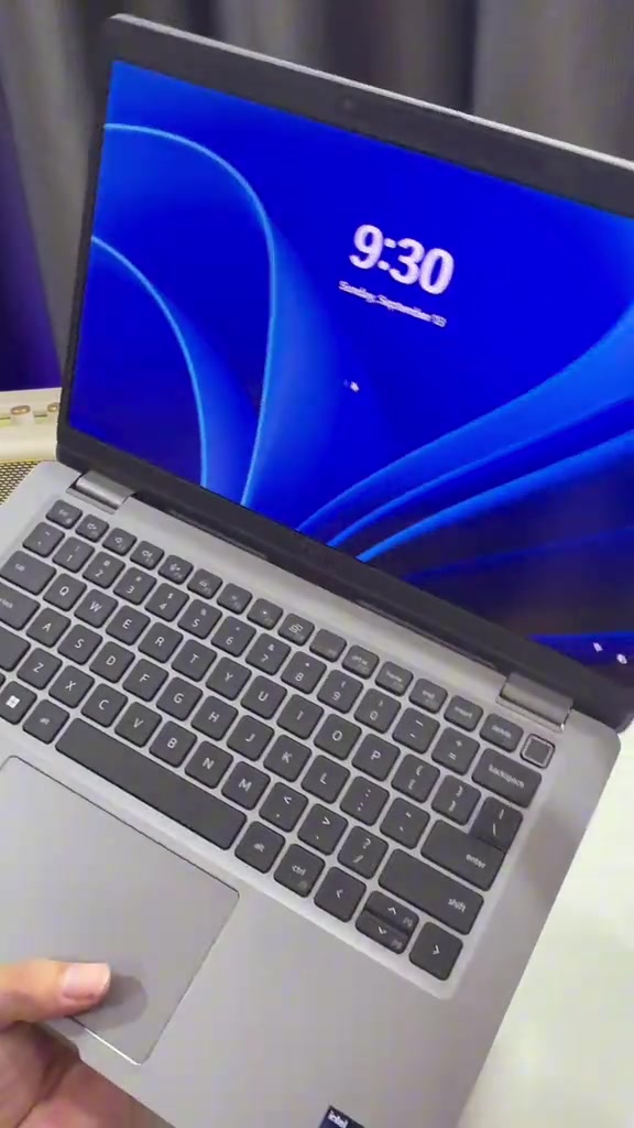 Cận cảnh bàn phím và màn hình khóa Windows 11 của một laptop Dell Latitude màu xám bạc