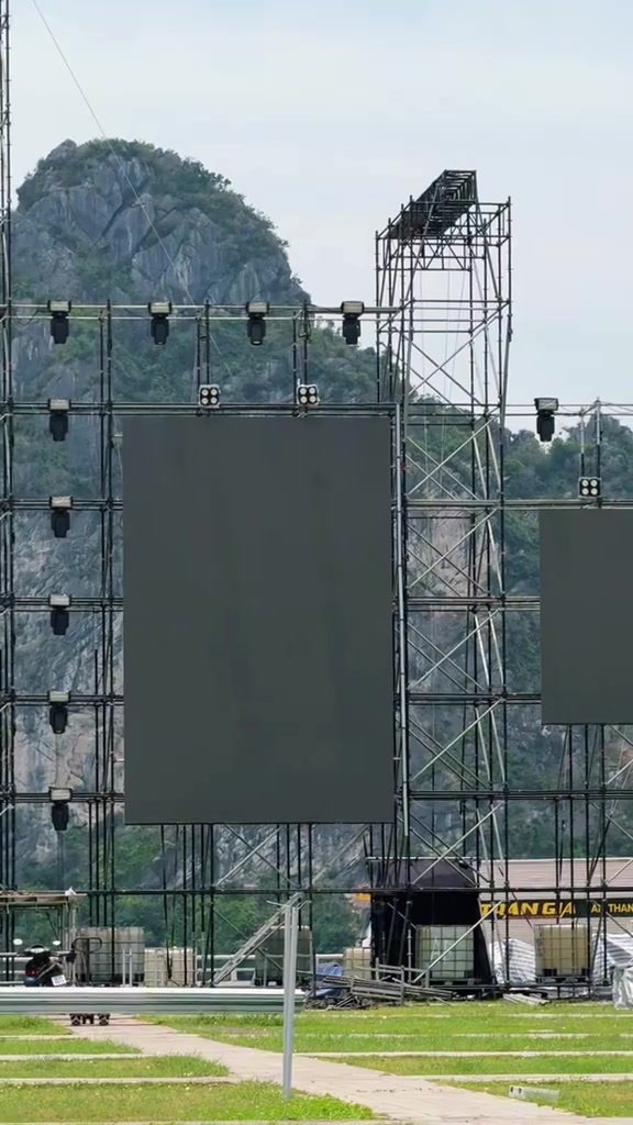 Giàn giáo thép treo màn hình LED và hàng đèn sân khấu của Y-FEST dựng ngoài trời, phía sau là núi đá ở chặng Quảng Ninh