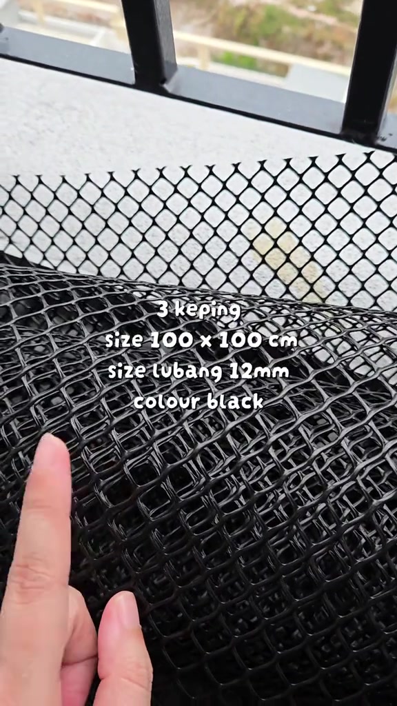 Tangan memegang jaring plastik hitam lubang 12 mm saiz 100 x 100 cm untuk tutup grill balkoni kucing