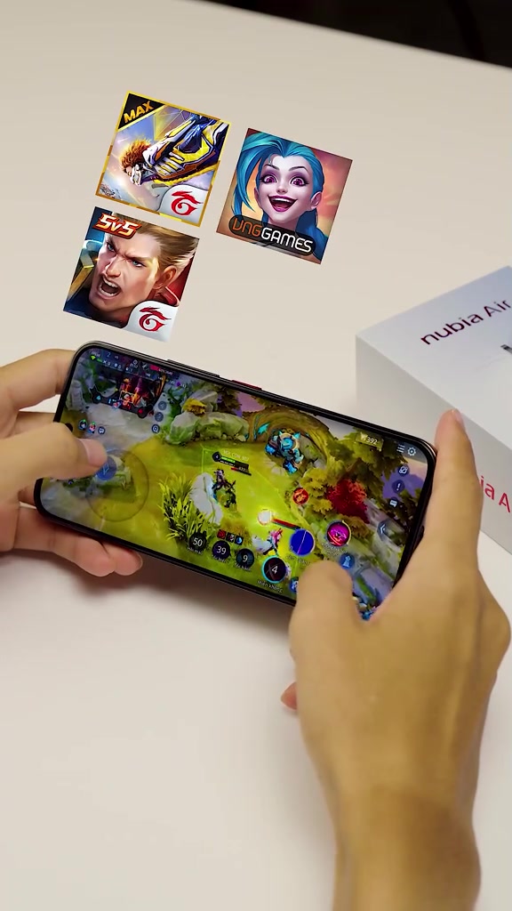 Hai tay cầm ngang điện thoại chơi game MOBA trên bàn trắng, bên cạnh là hộp giấy in chữ nubia Air