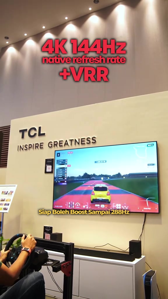 TV TCL dipasang di dinding menampilkan permainan video kereta dengan papan tanda 4K 144Hz native refresh rate dan VRR di atasnya