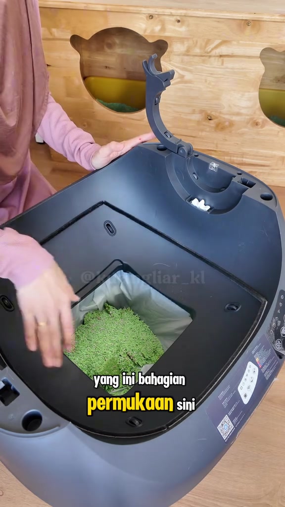 Bahagian dalam kotak pasir automatik berisi pasir tofu hijau dengan bekas sisa berlapis beg di bawah