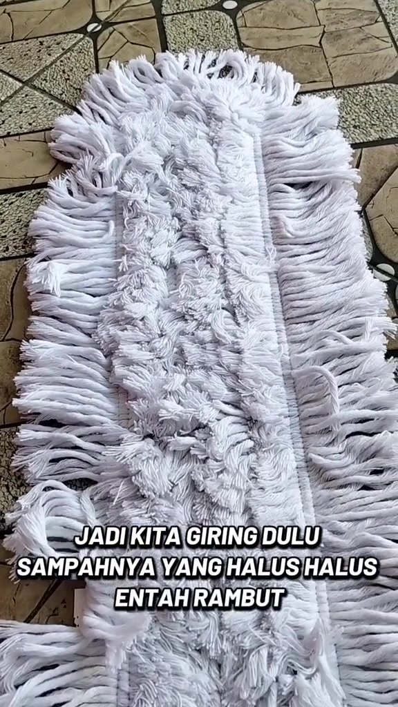 Kepala mop tali putih dibaringkan atas lantai untuk membuang habuk halus dan rambut