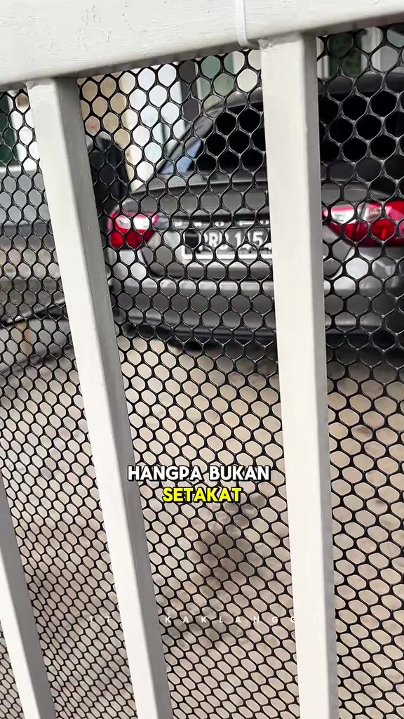 Jaring plastik hitam dipasang kemas pada palang grill putih balkoni apartment, diikat dengan cable tie di bahagian atas