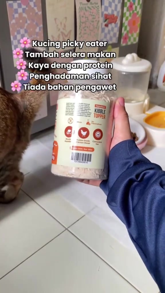 Tangan memegang balang Nanovet Kibble Topper berisi serbuk flakes ayam