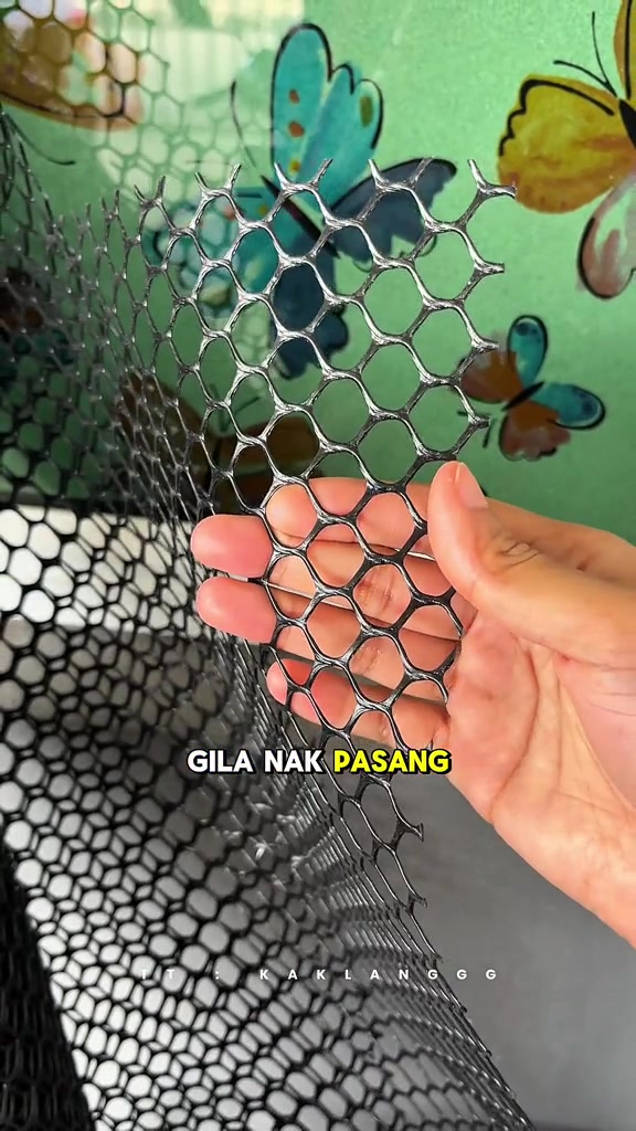 Tangan memegang sekeping jaring plastik hitam menunjukkan saiz lubang sebelum diperiksa dan dipasang