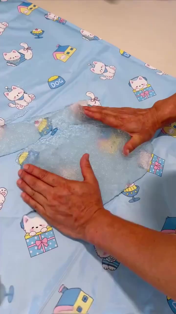 Dua tangan menekan lapisan gel di dalam cooling mat bercorak kucing