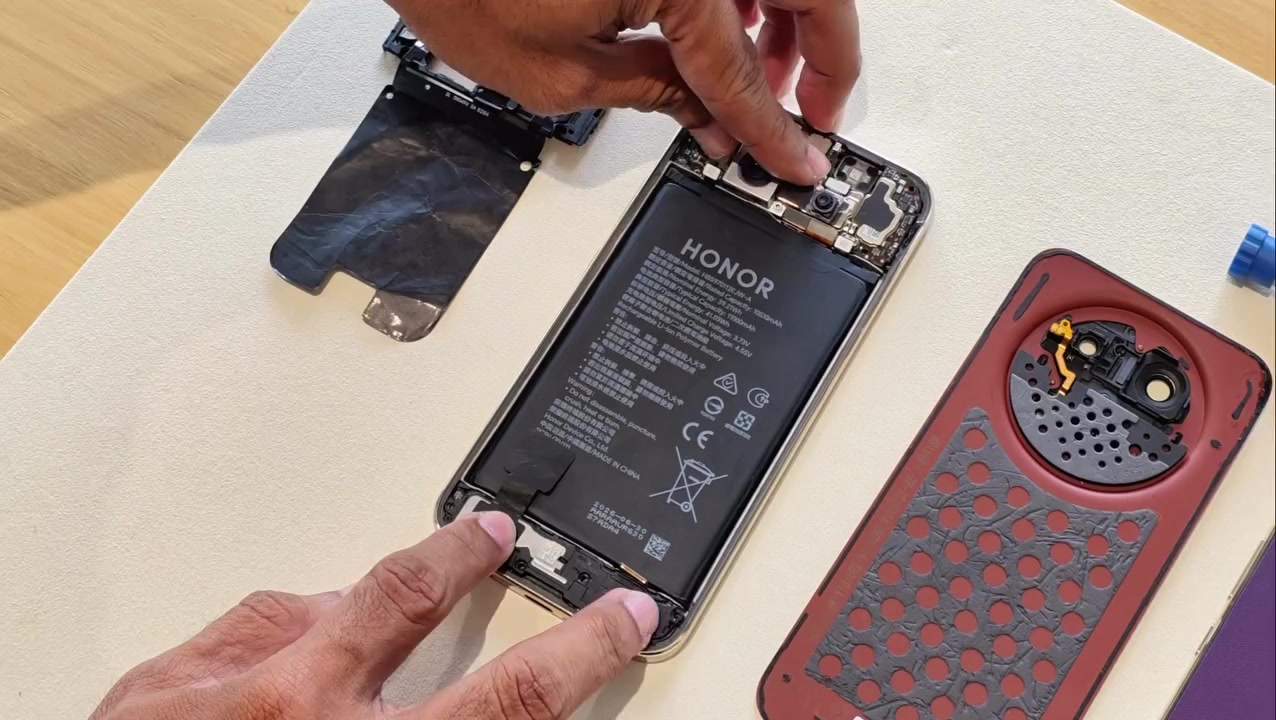 Badan HONOR X9e Pro terbuka dengan bateri 11,000mAh kelihatan, back cover merah berlapis foam di sebelah