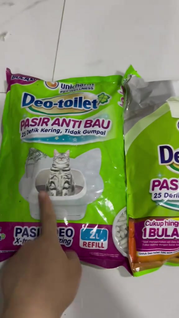 Tangan menunjuk pek isi semula pasir Deo-toilet 2L berlabel tidak menggumpal dan kering 25 saat