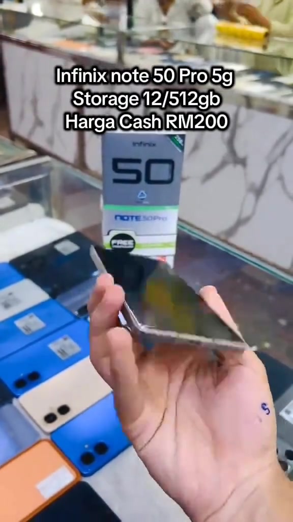 Tangan memegang telefon di hadapan kotak Infinix Note 50 Pro di kaunter kedai, teks bertindih pada video menyatakan storage 12/512gb harga cash RM200