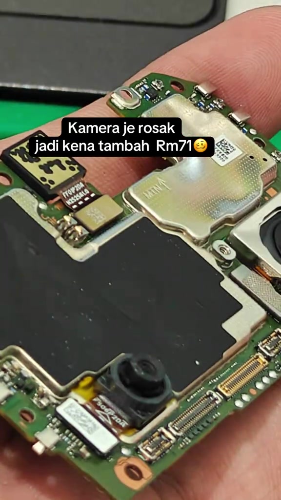 Papan litar utama telefon Honor dipegang dekat kamera, modul kamera rosak dan di luar liputan retak