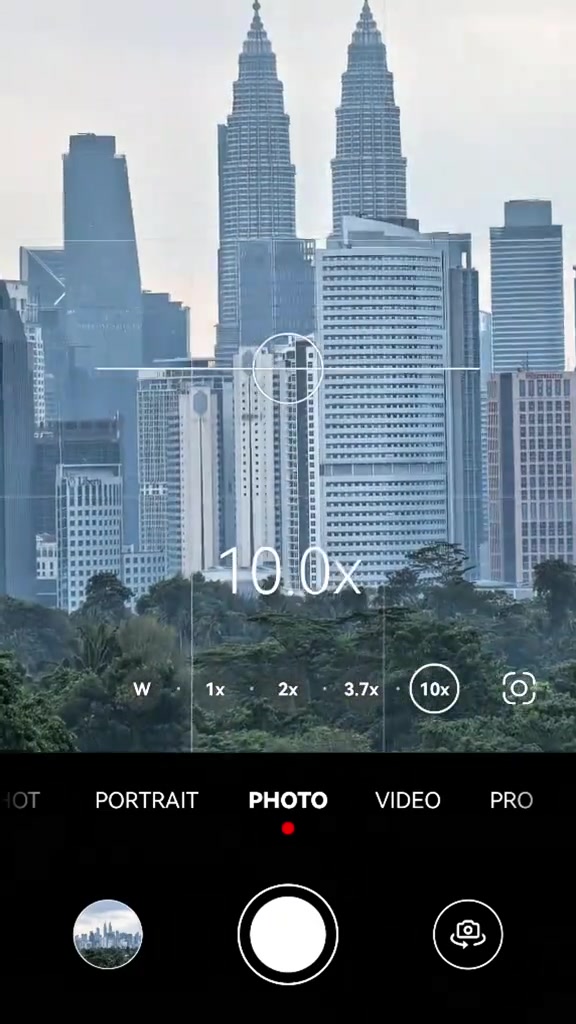 Skrin telefon menunjukkan antara muka kamera zum 10x menghala ke menara berkembar Kuala Lumpur