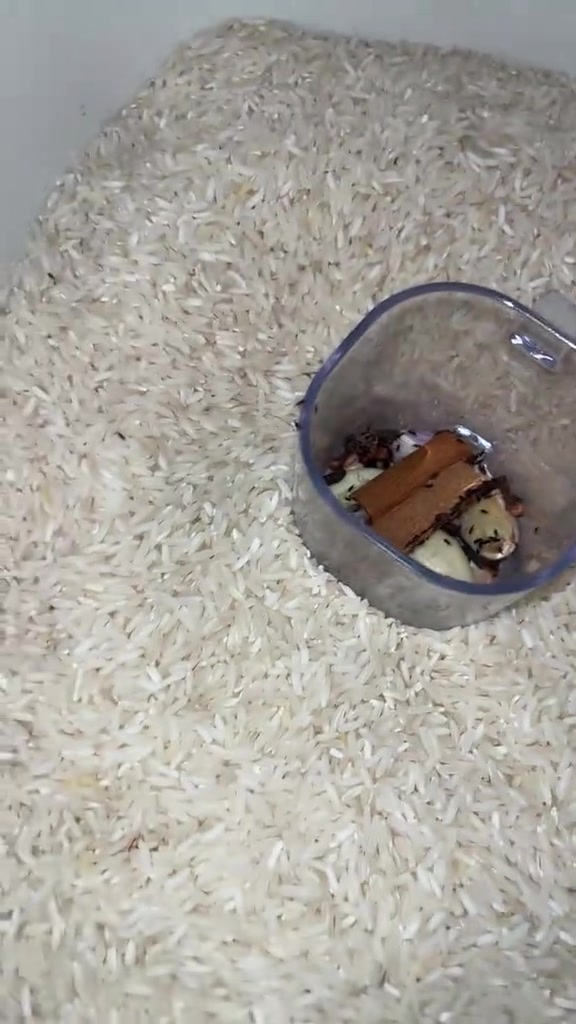 Mangkuk kecil berisi kayu manis, cengkih dan bawang putih ditanam di tengah bekas beras putih