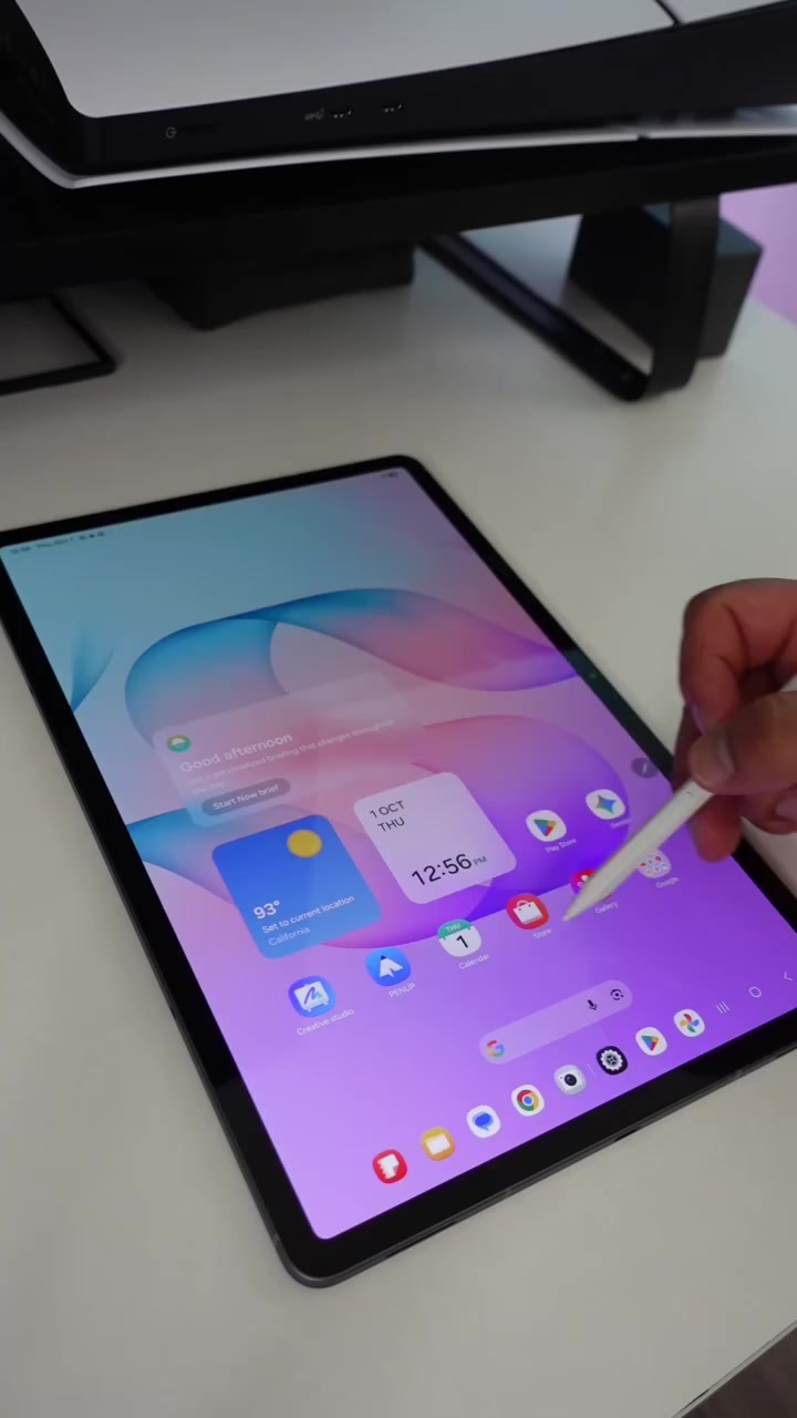 Galaxy Tab S12+ terbaring di atas meja putih dengan tangan memegang S Pen di atas skrin