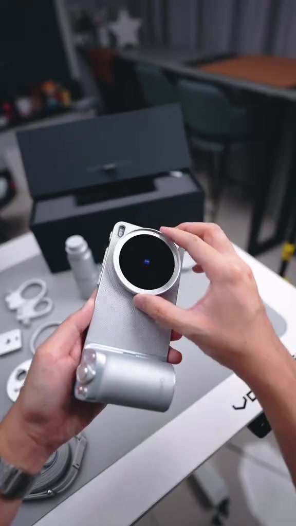 Tangan memasang kit grip fotografi pada vivo X300 Ultra warna perak di atas meja dengan aksesori kit