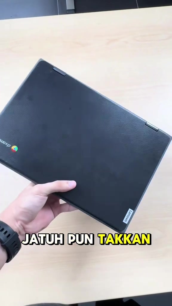 Tangan memegang Lenovo Chromebook hitam tertutup menunjukkan badan lasaknya