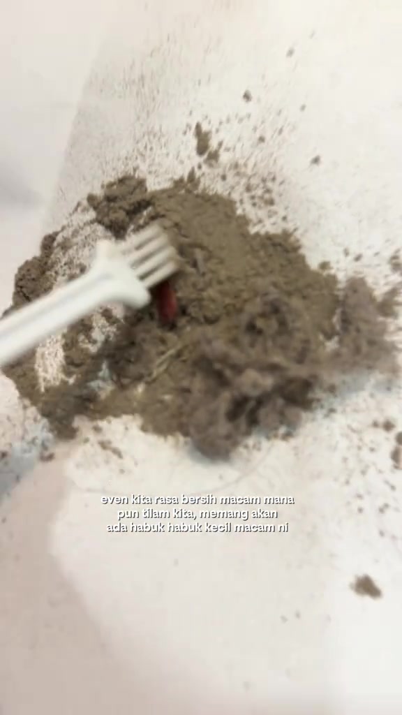 Berus kecil sedang membersihkan longgokan habuk halus kelabu dari dalam cup dust mite vacuum