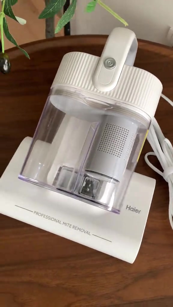 Dust mite vacuum Haier warna putih atas meja kayu, cup habuk telus nampak filter di dalamnya