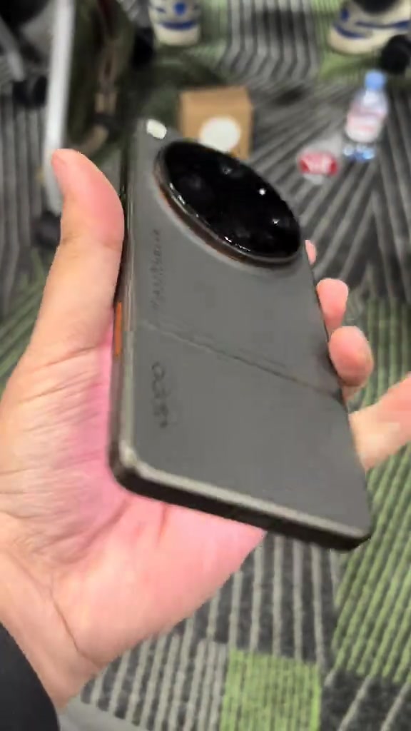 Tangan memegang OPPO Find X9 Ultra warna kelabu dari sudut sisi menunjukkan modul kamera bulat besar