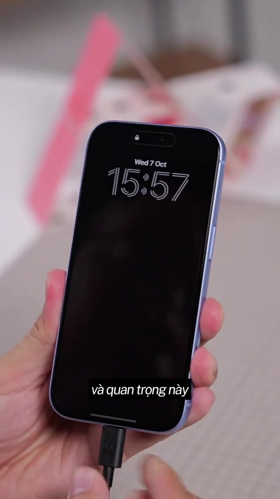 Một chiếc iPhone đang cắm cáp sạc, màn hình khoá hiện thứ và ngày