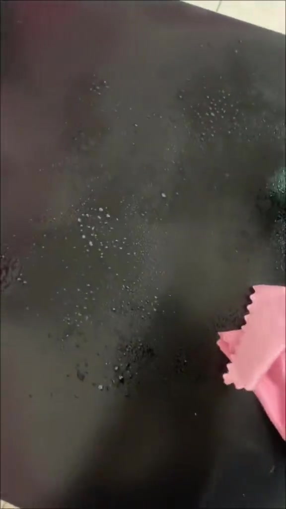 Kain pink mengelap permukaan gelap yang baru dibasuh