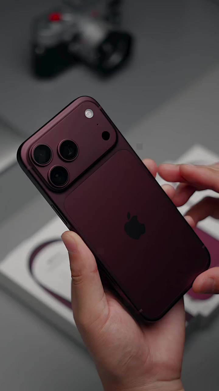 iPhone 18 Pro Max màu burgundy cầm nghiêng trên tay, thấy rõ cụm ba camera trên tấm kính ngang