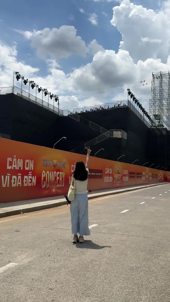Bức tường cam in chữ cảm ơn khán giả chạy dài trước khán đài concert tại The Global City, một cô gái đứng nhìn từ phía sau